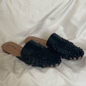 Wonderly brand mules feature a black woven design and a slip-on style